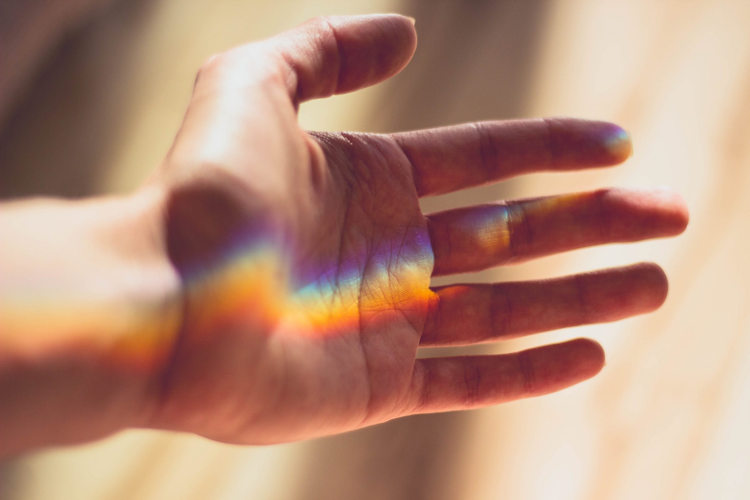 Hand met kleuren in licht als metafoor voor verschillende aanpak van veranderingen.