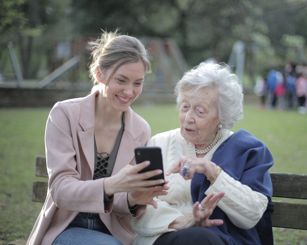 Vrouw en oudere dame in gesprek op een bankje in het park