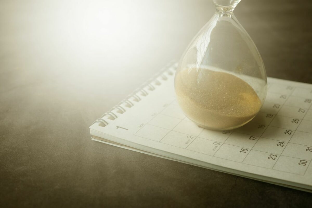 Een opengeslagen kalender met daarop een zandloper
